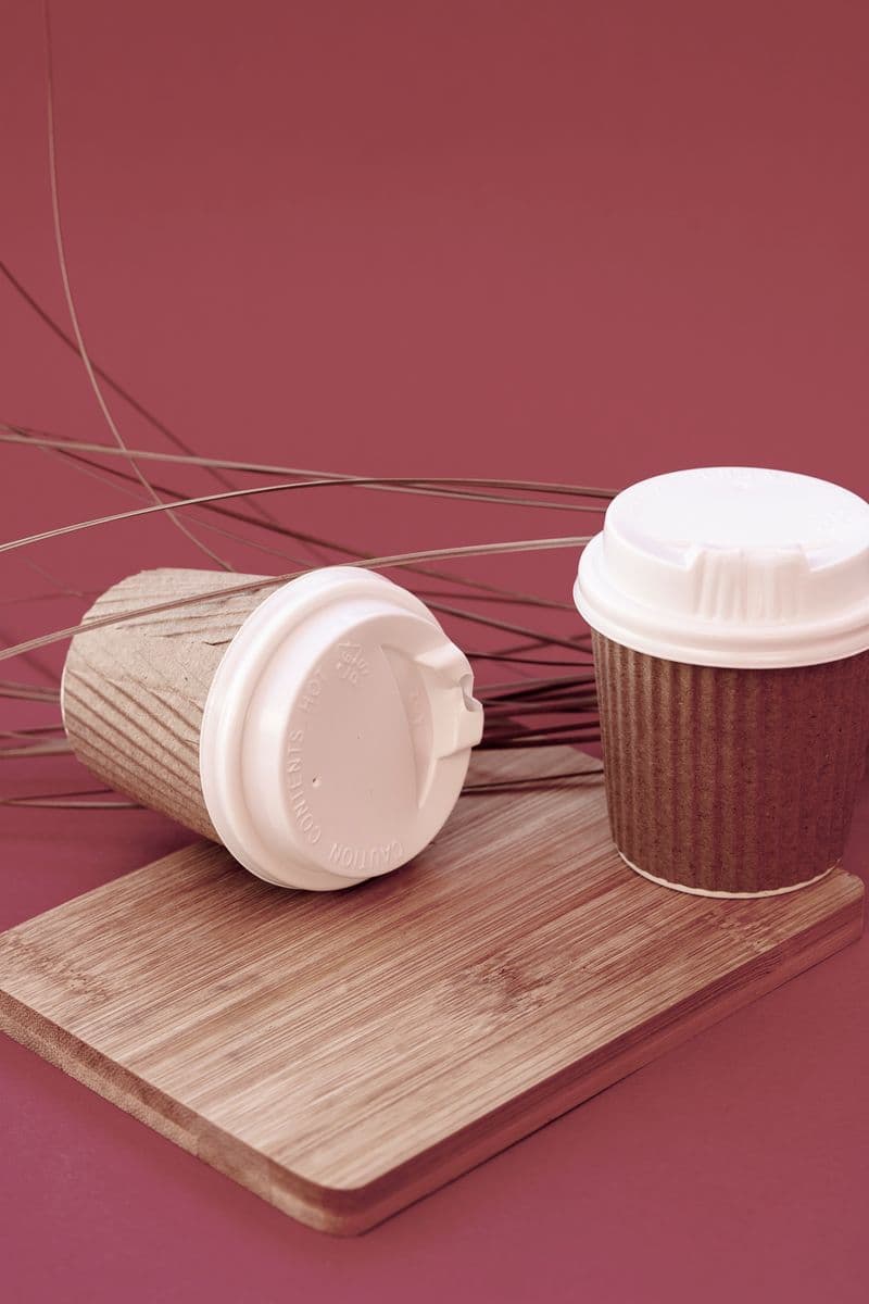 Paper cups with lids on wooden board